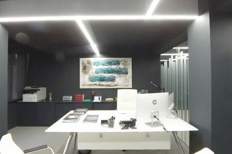 Despacho con mesa blanca, ordenador y un cuadro abstracto en tonos azules