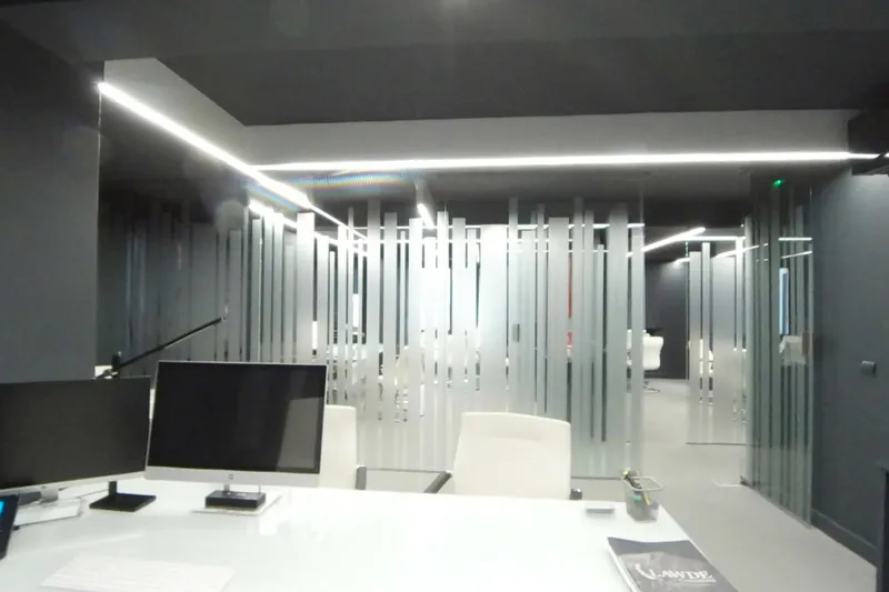 Despacho con mesa de trabajo y ordenadores, separado del pasillo por mamparas de cristal